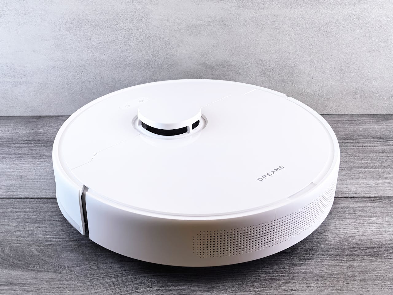 Sleek white robot vacuum cleaner on a wooden floor, perfect for smart home setups.